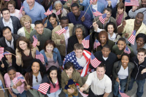 Diverse group of individuals holding small American flags while smiling at the camera.